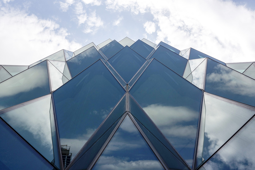 Some of the diamond-shaped panels tilt downwards, but are framed by triangular surfaces that connect them to the vertical supporting structure.