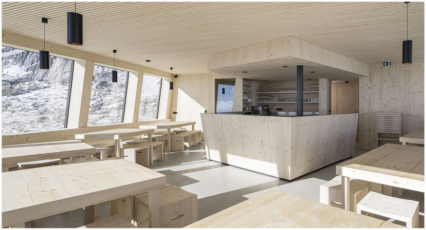 In the light-flooded dining area, a continuous band of windows grants guests a 180-degree panoramic view of the mountains. In the bar area, you can see the Velux window through which guests can be served on the terrace.