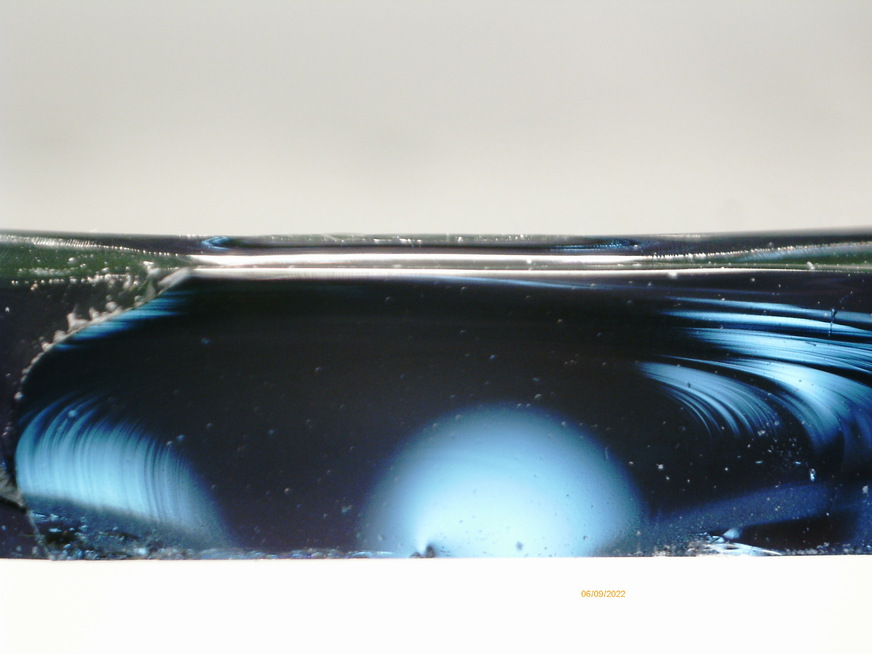 Detail of the fracture mirror, exactly in the middle at the lower edge the beginning of the pressure jump can be seen at the irregularity (arrow), as the greatest tensile stress occurred here.