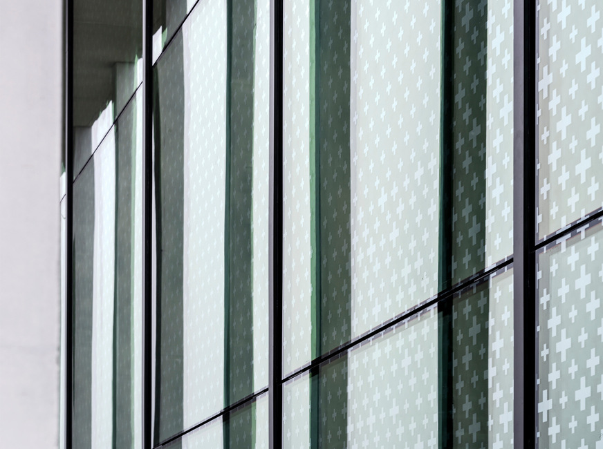 Frauenfeld barracks: Here is a view of the glass from the inside, which, in addition to providing bird protection, also serves as sun/glare protection. The motif of the bird protection glazing consists of many small crosses that condense into one large cross in the centre of the pane.