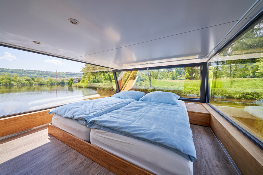 The upper sleeping area is a particular highlight of the houseboat: Here you can start the day with an all-round view, looking out over the water. The window can simply be tilted inwards for ventilation.