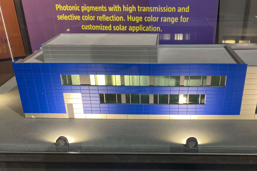 Conny Hahn, Product Manager in the business fields Facade and Interiors at building company Sto, in front of a demonstrator of a black facade incorporating solar modules from Sonnenkraft: