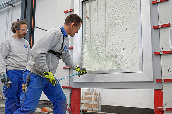 Two test engineers trying to break into a window.