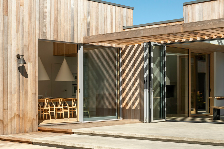 The aluminium profiles of the windows and glass folding walls are in a subtle light grey, which matches the cedar wood facade, which will develop a natural patina over time.