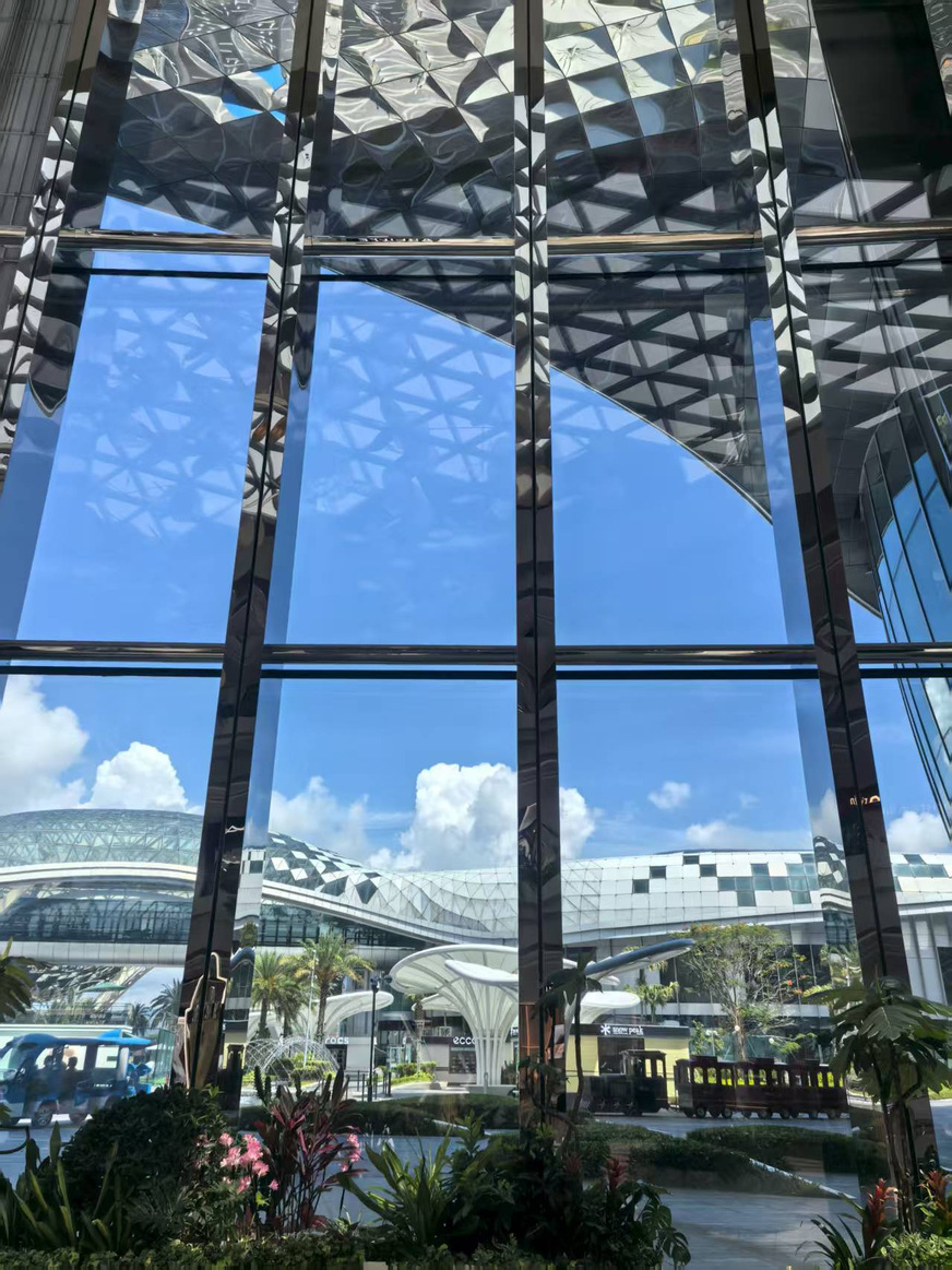 View through the glass façade of the Sanya International Duty Free Shopping Complex: the large-format insulating glass units with Ködispace 4SG provide an unobstructed view of the organically curved roof landscape.
