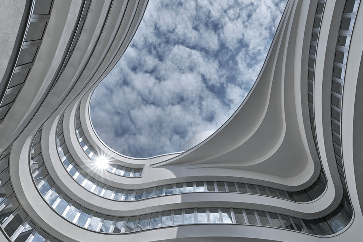 In the new building, horizontal bands of glass and snow-white glazed large-format ceramic tiles wrap themselves around the building as if on a seemingly endless band.