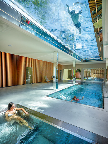 32 m of ceiling made from glass and water: the transparent bottom of the pool provides a special swimming experience and the water creates unique light effects in the interior of the building