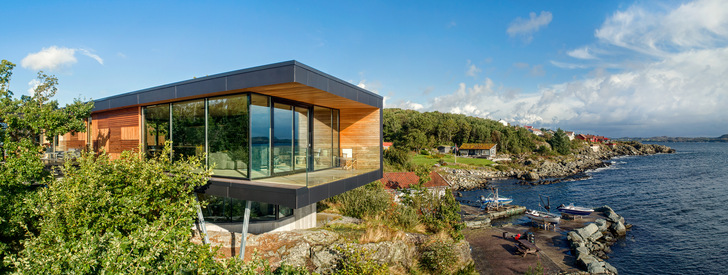 The nature in and around the Boknafjord shaped the design of the private home on the Norwegian island of Karmøy. While the concrete base with integrated ground floor appears wedded to the rocky ground, the top floor timber construction floats like a viewing platform above it.