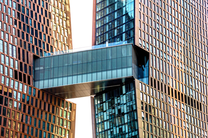 The Skybridge, the three-storey connecting bridge, is covered in glass with a metallic sheen. This is the result of a fine mesh that has been laminated into the outer LSG. - © Glas Trösch
