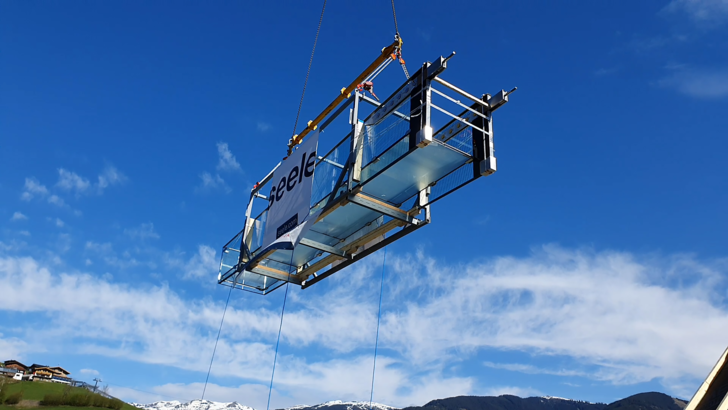 Floating: The glass walkway was lifted over the Bründl‘ Sports building to the installation site on the fourth floor with the help of a 45m long jib.