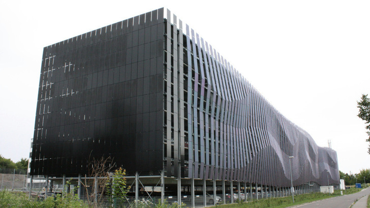 Modern black building with wavy pattern, multi-level parking visible below. - © Heiko Schwarzburger