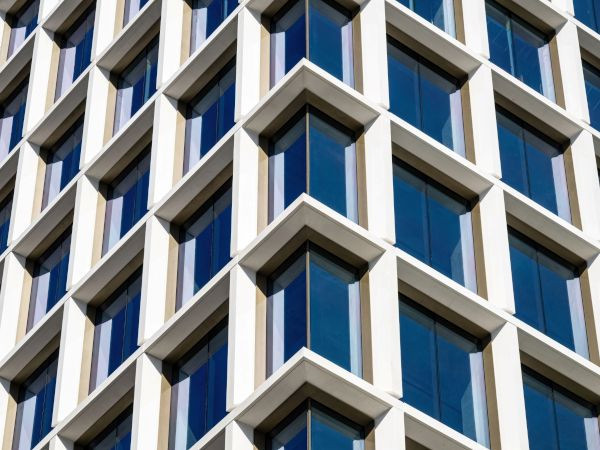 Modern building façade with geometric, grid-like windows and white frames reflecting the blue sky. - © Terry Wieckert - Abstract Photography, Inc.