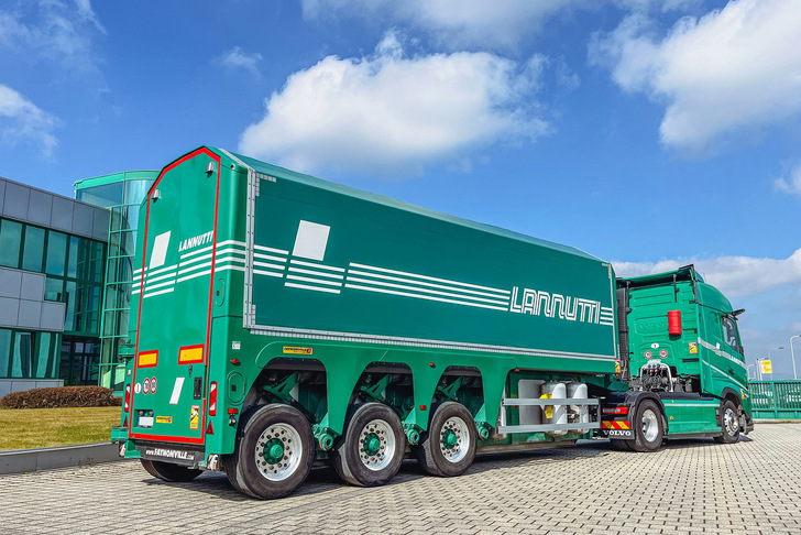 A green LANUMI branded semi-truck with a trailer is parked on a paved area near a modern glass building. - © Lannutti Group