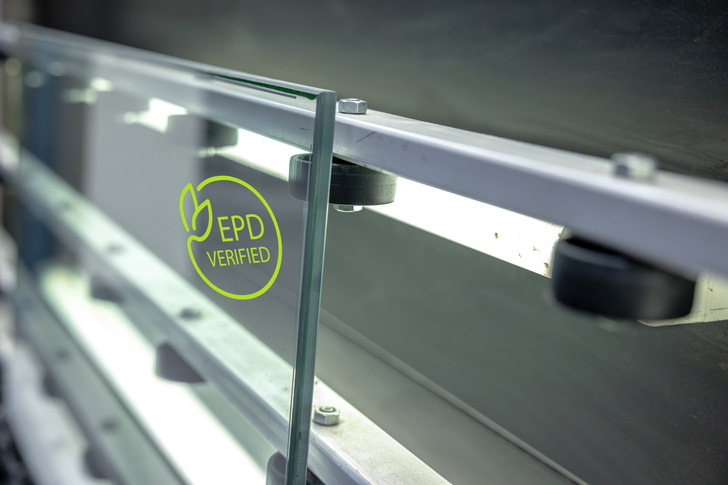 Nahaufnahme einer Glasscheibe mit EPD-geprüftem" Umweltzeichen, die an einem Metallgeländer angebracht ist. - © Fineo