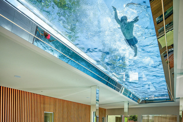  32 m of ceiling made from glass and water: the transparent bottom of the pool provides a special swimming experience and the water creates unique light effects in the interior of the building