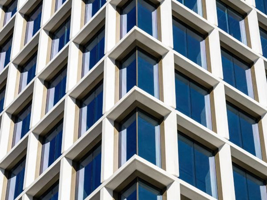 Modern building façade with geometric, grid-like windows and white frames reflecting the blue sky. - © Terry Wieckert - Abstract Photography, Inc.