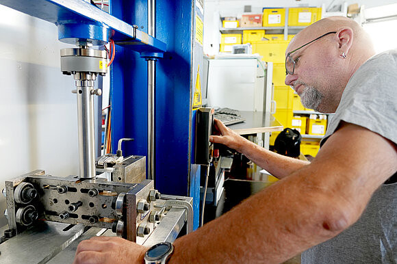 Test engineer operates test rig for testing profiles with thermal barrier according to DIN EN 14024.